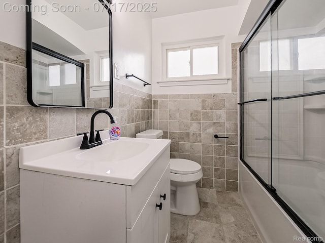 2314 Middlebelt Rd, West Bloomfield, MI 48324 - bathroom featuring tile walls, vanity, shower / bath combination with glass door, and a wainscoted wall