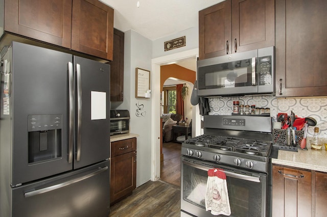 2136 Amherst Ave, Kalamazoo, MI 49008 - kitchen with appliances with stainless steel finishes, dark wood-type flooring, arched walkways, decorative backsplash, and dark brown cabinets