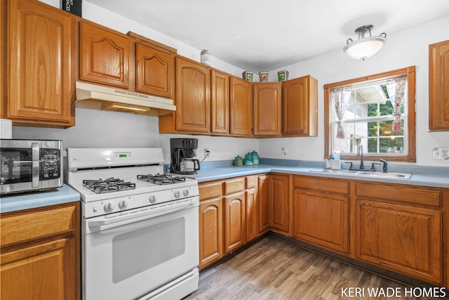 3231 E Baker Rd, Hesperia, MI 49421 - kitchen with white range with gas cooktop, under cabinet range hood, stainless steel microwave, light countertops, and light wood-style floors