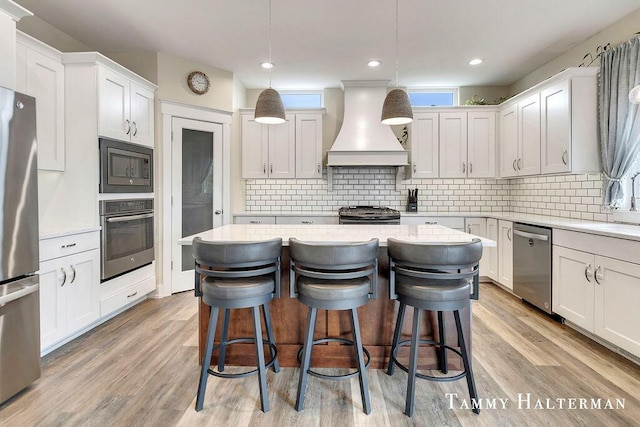 6129 W Bay Ct, Hudsonville, MI 49426 - kitchen featuring stainless steel appliances, custom exhaust hood, a center island, light countertops, and a breakfast bar