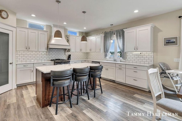6129 W Bay Ct, Hudsonville, MI 49426 - kitchen with custom range hood, appliances with stainless steel finishes, a breakfast bar, light countertops, and a center island