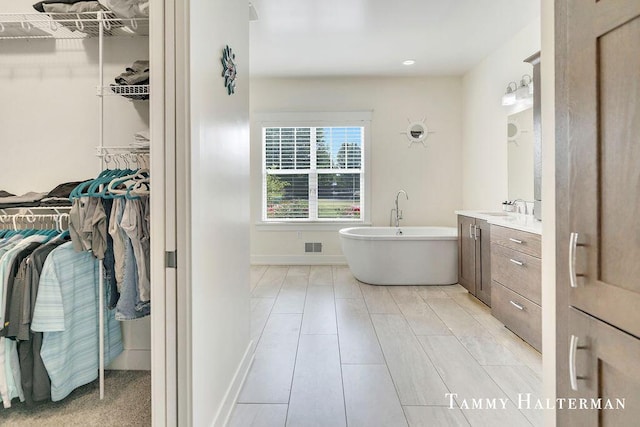 6129 W Bay Ct, Hudsonville, MI 49426 - full bathroom with vanity, a freestanding bath, a walk in closet, and recessed lighting