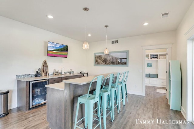6129 W Bay Ct, Hudsonville, MI 49426 - indoor wet bar with wine cooler, light wood finished floors, decorative light fixtures, and recessed lighting