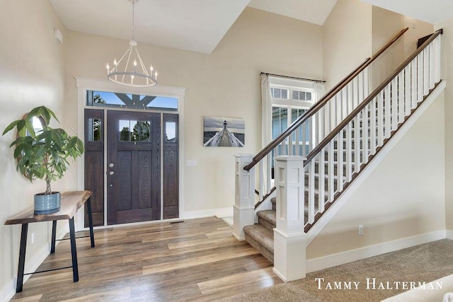 6129 W Bay Ct, Hudsonville, MI 49426 - entrance foyer featuring a chandelier, stairway, wood finished floors, and high vaulted ceiling