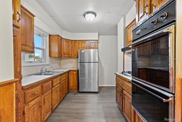 8460 Busko Ave, Utica, MI 48093 - kitchen with appliances with stainless steel finishes, light countertops, brown cabinets, light wood finished floors, and decorative backsplash