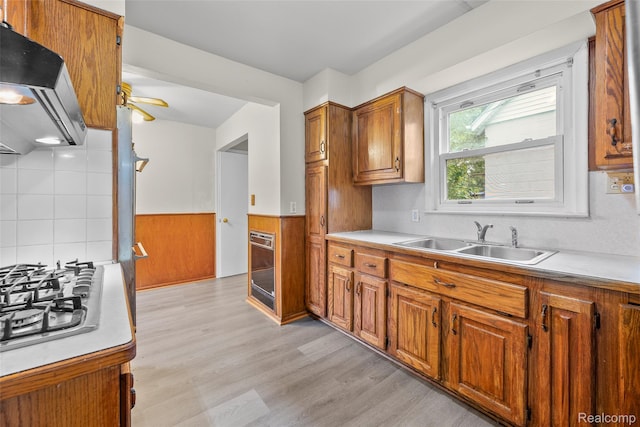 8460 Busko Ave, Utica, MI 48093 - kitchen with range hood, stainless steel gas stovetop, brown cabinetry, a wainscoted wall, and light countertops