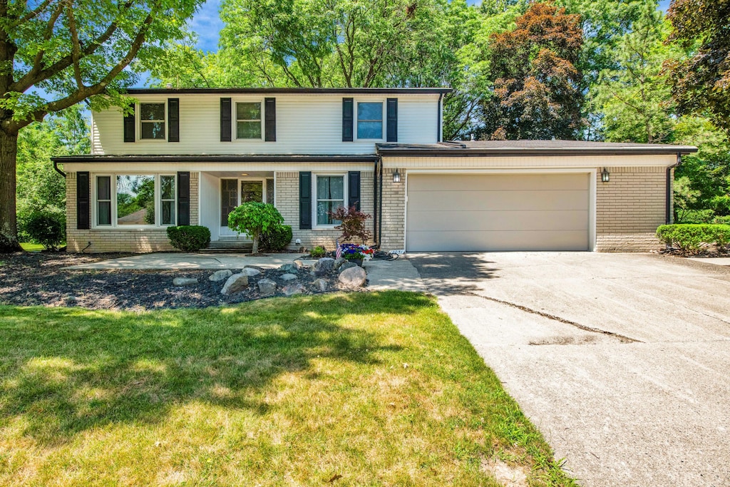 12051 Wildwing Rd, Plymouth, MI 48170 - traditional-style house featuring brick siding, driveway, an attached garage, and a front lawn
