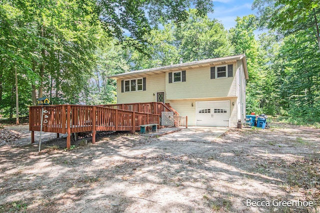 14180 168th Ave, Grand Haven, MI 49417 - back of house featuring an attached garage, a wooden deck, driveway, and view of wooded area