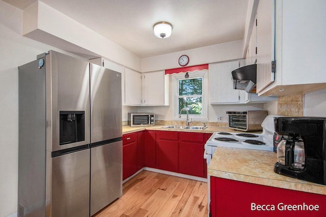 14180 168th Ave, Grand Haven, MI 49417 - kitchen with stainless steel appliances, light countertops, light wood-style floors, exhaust hood, and white cabinetry