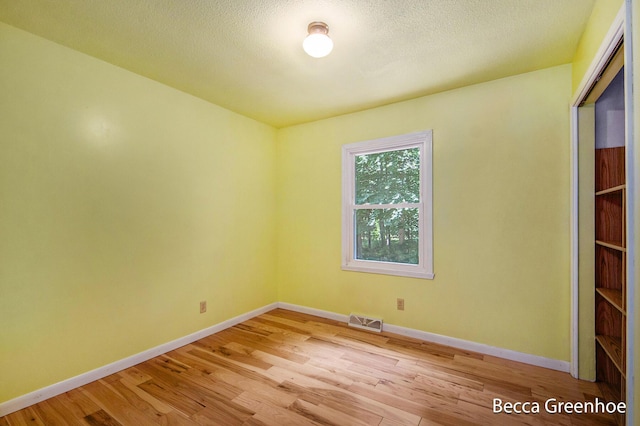 14180 168th Ave, Grand Haven, MI 49417 - unfurnished bedroom featuring light wood-type flooring, a closet, and a textured ceiling