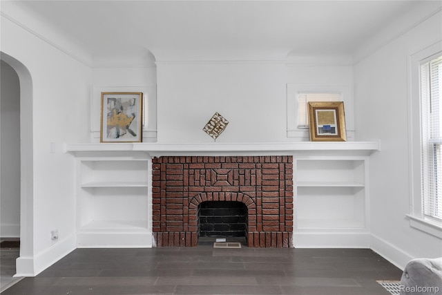 3921 Three Mile Dr, Detroit, MI 48224 - unfurnished living room featuring built in features, a fireplace, wood finished floors, and arched walkways