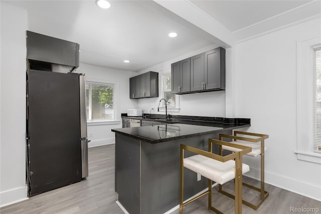 3921 Three Mile Dr, Detroit, MI 48224 - kitchen featuring appliances with stainless steel finishes, a peninsula, light wood finished floors, a kitchen bar, and recessed lighting