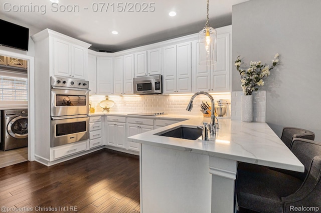 23331 Sawgrass Ct S, South Lyon, MI 48178 - kitchen featuring washer / clothes dryer, stainless steel appliances, a peninsula, white cabinets, and recessed lighting