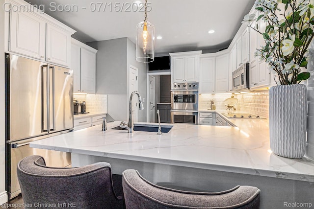23331 Sawgrass Ct S, South Lyon, MI 48178 - kitchen with appliances with stainless steel finishes, a peninsula, white cabinetry, decorative backsplash, and recessed lighting