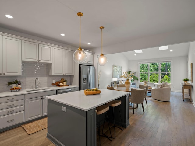 3064 N Spurway Dr, Ann Arbor, MI 48105 - kitchen featuring stainless steel appliances, open floor plan, a kitchen island, light countertops, and light wood-style floors
