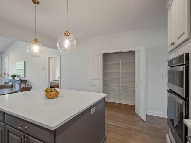 3064 N Spurway Dr, Ann Arbor, MI 48105 - kitchen featuring stainless steel double oven, dark wood-style flooring, pendant lighting, gray cabinets, and a kitchen island