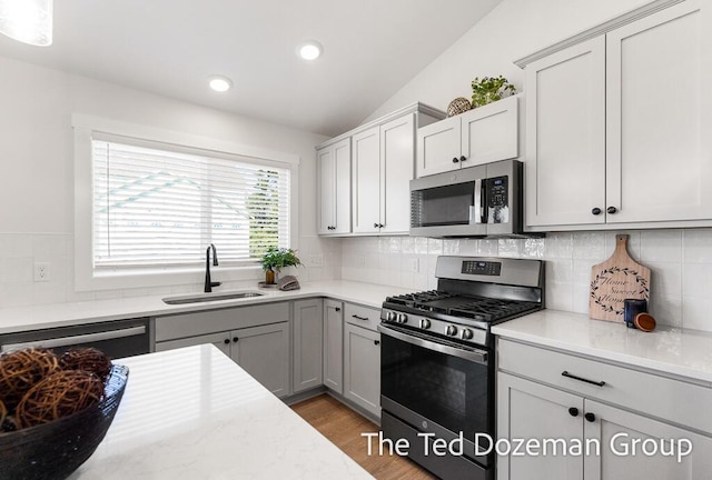 3171 Timberpine Ave, Holland, MI 49424 - kitchen with appliances with stainless steel finishes, lofted ceiling, light wood-style flooring, recessed lighting, and backsplash
