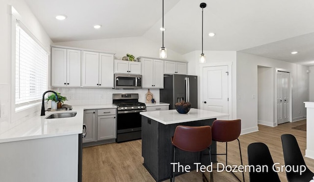 3171 Timberpine Ave, Holland, MI 49424 - kitchen with appliances with stainless steel finishes, light wood-type flooring, tasteful backsplash, a center island, and vaulted ceiling