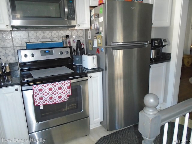kitchen with appliances with stainless steel finishes, dark countertops, white cabinets, and backsplash