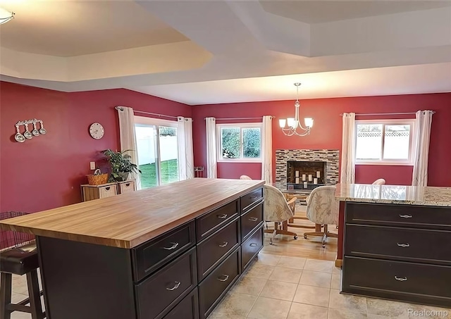 10352 Gulley St, Taylor, MI 48180 - kitchen featuring wood counters, a tray ceiling, a breakfast bar area, a chandelier, and light tile patterned floors