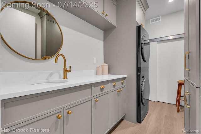 2051 Villa Rd Unit 302, Birmingham, MI 48009 - laundry area with stacked washer and clothes dryer, cabinet space, and light wood-type flooring