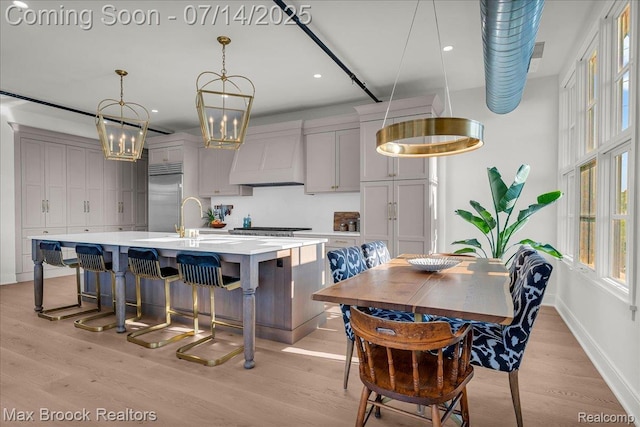 2051 Villa Rd Unit 302, Birmingham, MI 48009 - kitchen with appliances with stainless steel finishes, premium range hood, light countertops, a kitchen island with sink, and light wood-style floors