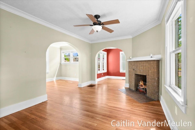 1340 Ashland Ave NE, Grand Rapids, MI 49505 - unfurnished living room with a fireplace, wood finished floors, ornamental molding, a ceiling fan, and arched walkways
