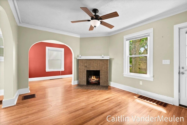 1340 Ashland Ave NE, Grand Rapids, MI 49505 - unfurnished living room featuring a ceiling fan, a fireplace, wood finished floors, and crown molding
