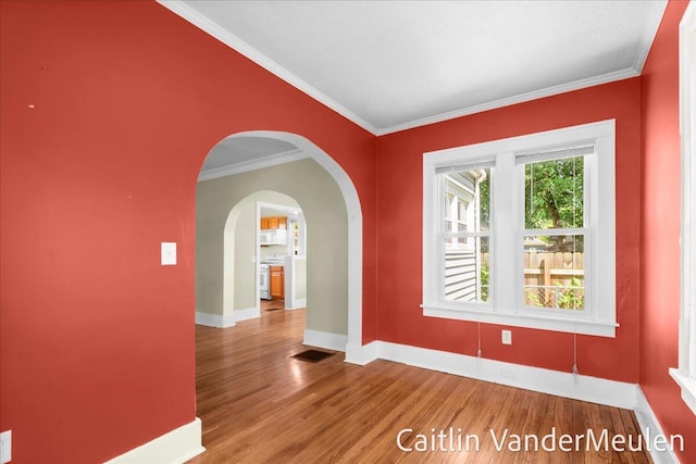 1340 Ashland Ave NE, Grand Rapids, MI 49505 - unfurnished room featuring wood finished floors, crown molding, and arched walkways