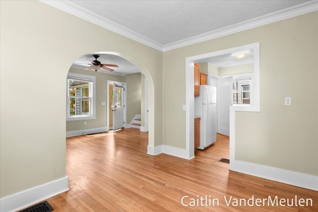 1340 Ashland Ave NE, Grand Rapids, MI 49505 - empty room featuring arched walkways, light wood-style flooring, crown molding, stairs, and a ceiling fan