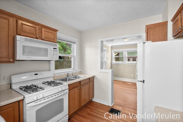 1340 Ashland Ave NE, Grand Rapids, MI 49505 - kitchen with white appliances, light wood-type flooring, light countertops, brown cabinets, and a textured ceiling