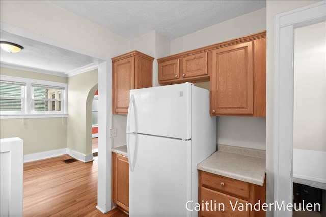 1340 Ashland Ave NE, Grand Rapids, MI 49505 - kitchen featuring freestanding refrigerator, light wood-type flooring, light countertops, arched walkways, and crown molding