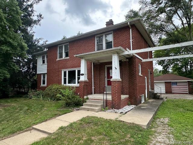 12100 Elmview St, Romulus, MI 48174 - view of front of home with brick siding, a chimney, an outdoor structure, a front yard, and a detached garage