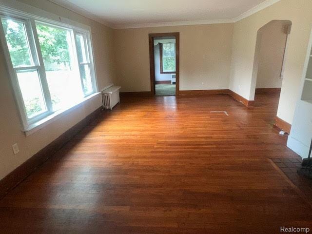 12100 Elmview St, Romulus, MI 48174 - spare room with radiator, crown molding, wood finished floors, and arched walkways