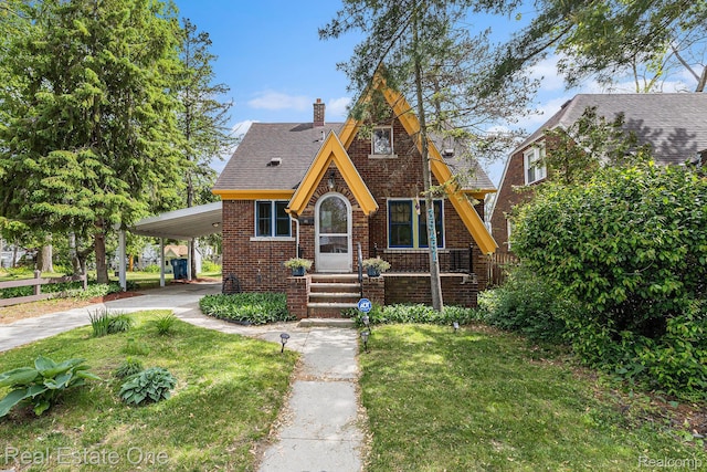 35451 John St, Wayne, MI 48184 - tudor home featuring an attached carport, a chimney, brick siding, a front yard, and driveway