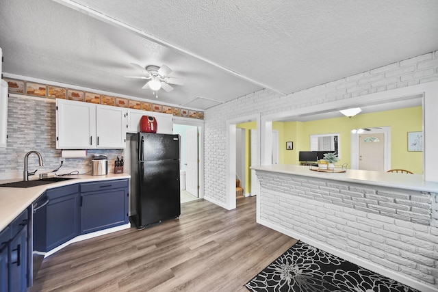 350 N Horton St, Jackson, MI 49202 - kitchen with freestanding refrigerator, ceiling fan, blue cabinetry, light wood-style flooring, and light countertops