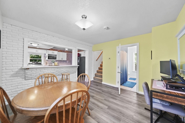350 N Horton St, Jackson, MI 49202 - dining room featuring a textured ceiling, wood finished floors, stairs, and brick wall