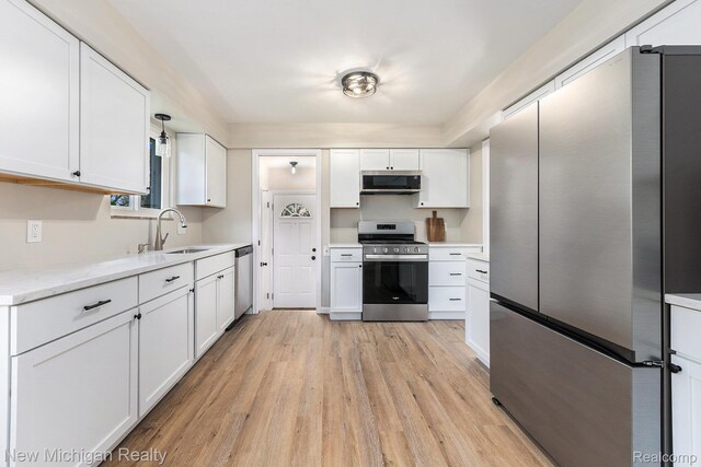23306 Greencrest St, Saint Clair Shores, MI 48080 - kitchen with appliances with stainless steel finishes, light wood-style flooring, white cabinets, and light countertops