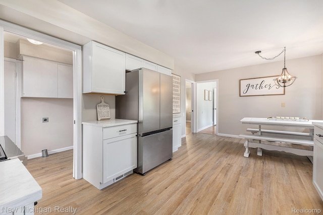 23306 Greencrest St, Saint Clair Shores, MI 48080 - kitchen featuring freestanding refrigerator, light wood-style flooring, white cabinetry, light countertops, and pendant lighting