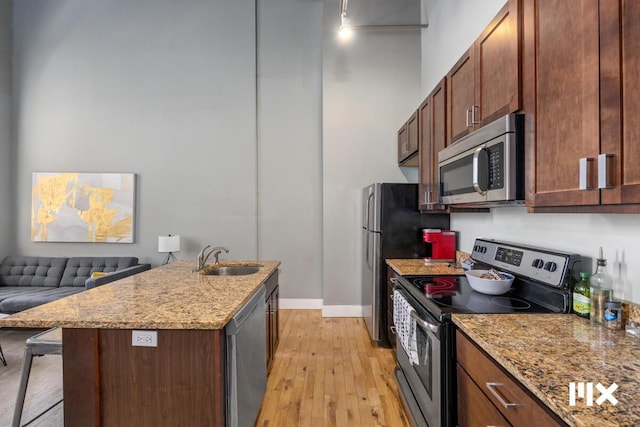 139 Pearl St NW, Grand Rapids, MI 49503 - kitchen featuring stainless steel appliances, light wood-style flooring, light stone counters, a kitchen breakfast bar, and a kitchen island with sink