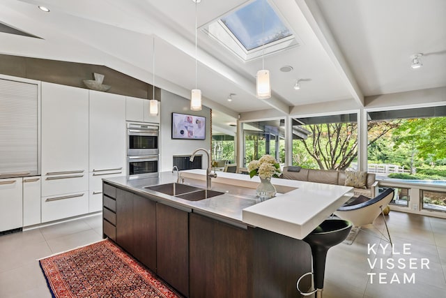 130 Robinwood Ave SE, Grand Rapids, MI 49506 - kitchen with double oven, a skylight, light tile patterned floors, a large island, and modern cabinets