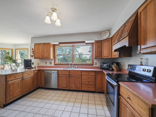 626 Skocelas Rd N, Manistee, MI 49660 - kitchen with appliances with stainless steel finishes, brown cabinets, a peninsula, a chandelier, and light tile patterned floors