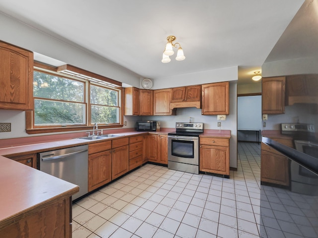 626 Skocelas Rd N, Manistee, MI 49660 - kitchen with stainless steel appliances, light tile patterned floors, brown cabinets, under cabinet range hood, and light countertops