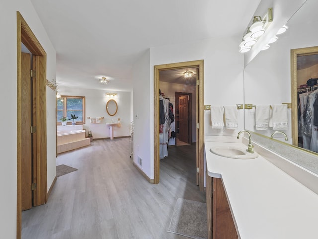 626 Skocelas Rd N, Manistee, MI 49660 - bathroom with a spacious closet, vanity, and wood finished floors