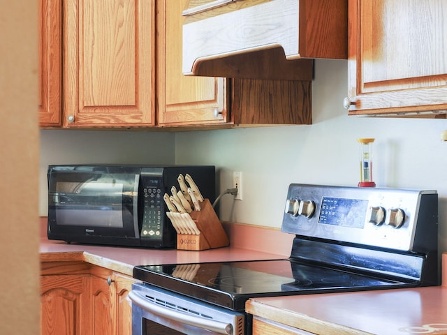 626 Skocelas Rd N, Manistee, MI 49660 - kitchen featuring stainless steel electric range, black microwave, exhaust hood, and light countertops