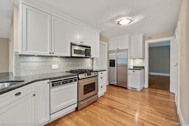 532 Wallace St, Southfield, MI 48009 - kitchen with appliances with stainless steel finishes, white cabinets, light wood-style flooring, and decorative backsplash