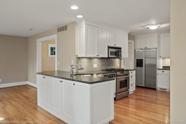 532 Wallace St, Southfield, MI 48009 - kitchen featuring appliances with stainless steel finishes, a peninsula, white cabinetry, tasteful backsplash, and light wood finished floors
