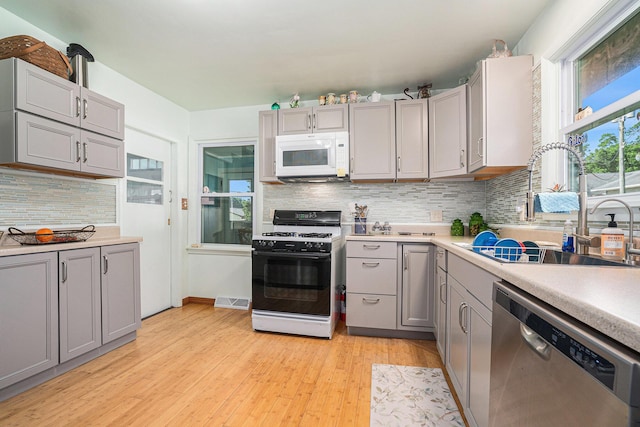 53266 US-131, Three Rivers, MI 49093 - kitchen with white appliances, gray cabinetry, light wood finished floors, light countertops, and decorative backsplash