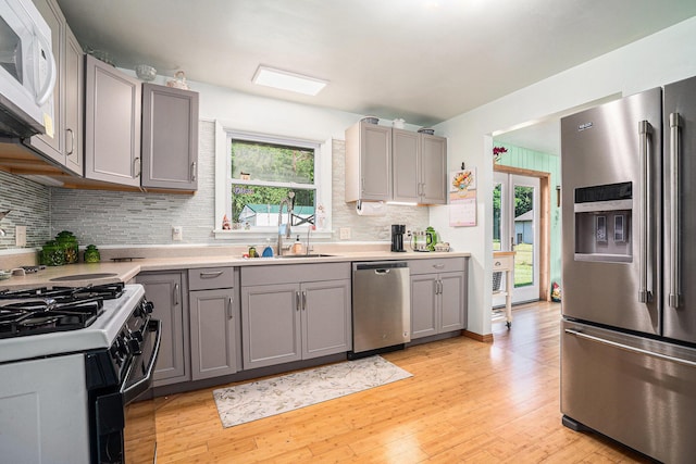 53266 US-131, Three Rivers, MI 49093 - kitchen featuring stainless steel appliances, gray cabinetry, light wood-style floors, tasteful backsplash, and light countertops