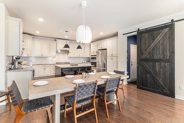 6217 S Trailwoods Dr, Ann Arbor, MI 48103 - kitchen featuring stainless steel appliances, a barn door, a center island, backsplash, and dark wood-style flooring